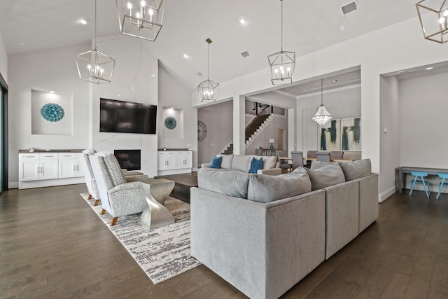 5318 Abington Creek Ln, Sugar Land, TX 77479 - living area featuring high vaulted ceiling, a high end fireplace, stairway, dark wood finished floors, and a chandelier