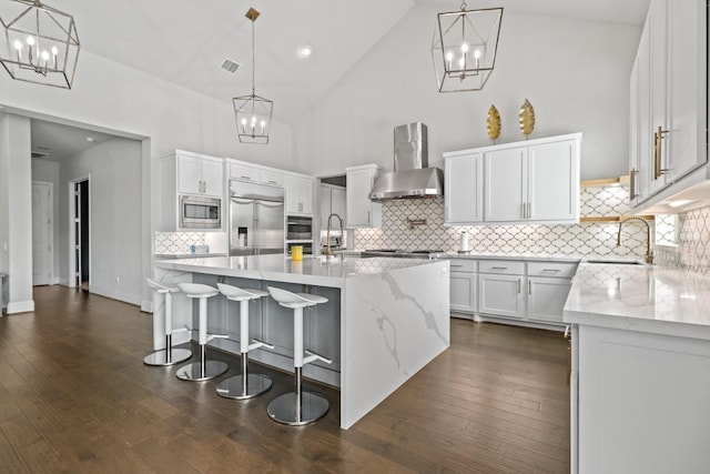 5318 Abington Creek Ln, Sugar Land, TX 77479 - kitchen with wall chimney range hood, built in appliances, a sink, high vaulted ceiling, and a chandelier