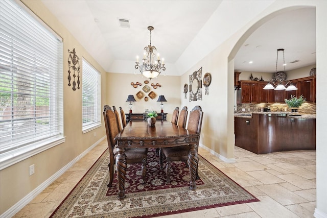 8917 Hawk Rd, Pearland, TX 77584 - dining room with a chandelier, arched walkways, baseboards, stone tile floors, and vaulted ceiling