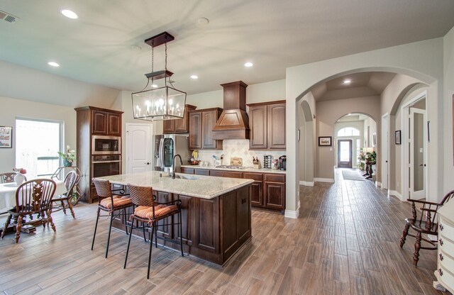 2335 Mayfield Trail Ct, League City, TX 77573 - kitchen with stainless steel appliances, a sink, a kitchen island with sink, a kitchen bar, and wood finished floors