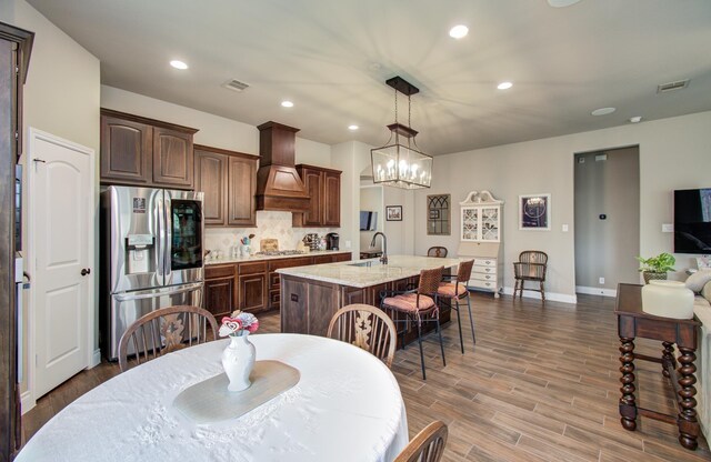 2335 Mayfield Trail Ct, League City, TX 77573 - kitchen with appliances with stainless steel finishes, custom exhaust hood, a sink, backsplash, and a kitchen island with sink