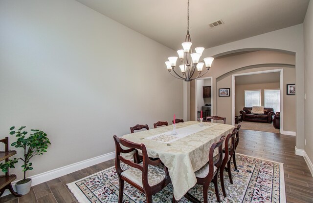 2335 Mayfield Trail Ct, League City, TX 77573 - dining area featuring arched walkways, a chandelier, dark wood-type flooring, and baseboards