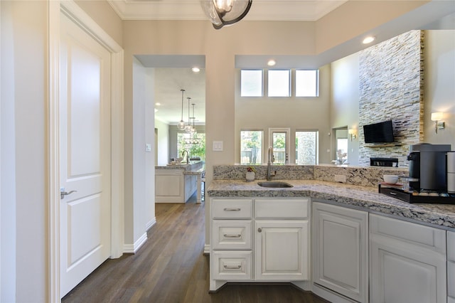 13706 Northwood Meadow Cir, Houston, TX 77077 - kitchen with a sink, a stone fireplace, light stone countertops, dark wood-style flooring, and crown molding