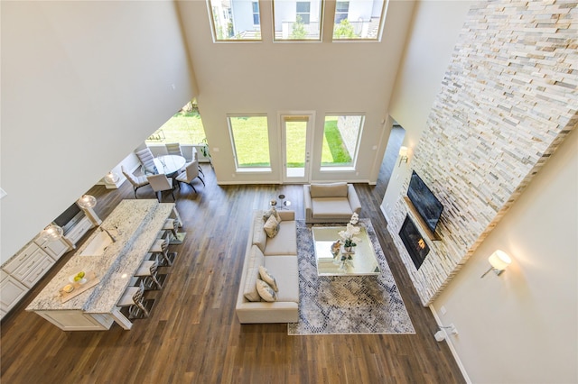 13706 Northwood Meadow Cir, Houston, TX 77077 - living room featuring a high ceiling, a glass covered fireplace, wood finished floors, and baseboards