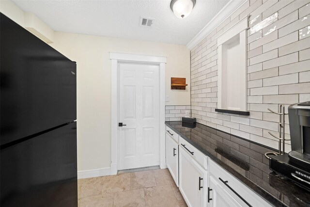 12986 Wood Harbour Dr, Montgomery, TX 77356 - kitchen featuring freestanding refrigerator, dark stone counters, white cabinetry, backsplash, and a textured ceiling