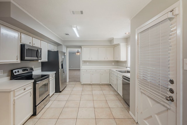19523 Enchanted Grove Dr, Spring, TX 77388 - kitchen featuring appliances with stainless steel finishes, ceiling fan, light countertops, white cabinetry, and light tile patterned floors