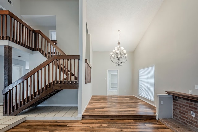 19523 Enchanted Grove Dr, Spring, TX 77388 - foyer with high vaulted ceiling, wood finished floors, stairway, a chandelier, and baseboards