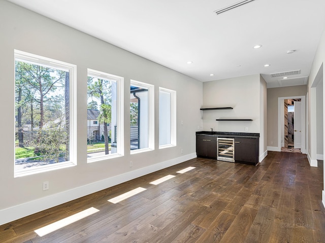 12914 Figaro Dr, Houston, TX 77024 - unfurnished living room with beverage cooler, bar with sink, baseboards, dark wood finished floors, and recessed lighting