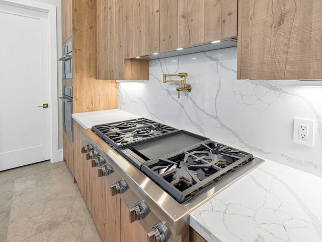 12914 Figaro Dr, Houston, TX 77024 - kitchen featuring decorative backsplash, oven, stainless steel gas cooktop, modern cabinets, and light stone counters