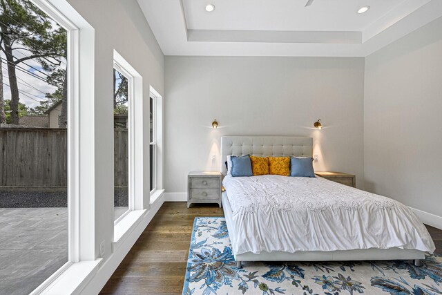 12914 Figaro Dr, Houston, TX 77024 - bedroom with dark wood finished floors, a tray ceiling, recessed lighting, and baseboards