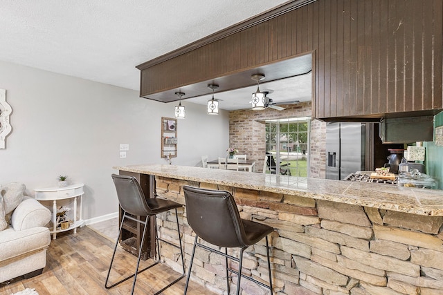 842 Broad Ripple Dr, Houston, TX 77336 - kitchen with light wood finished floors, ceiling fan, baseboards, a kitchen breakfast bar, and stainless steel fridge