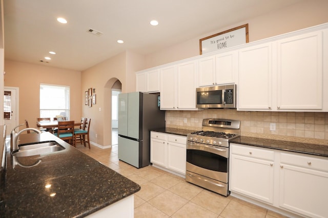 18123 Quarry Vale Dr, Cypress, TX 77429 - kitchen with appliances with stainless steel finishes, a sink, arched walkways, decorative backsplash, and recessed lighting