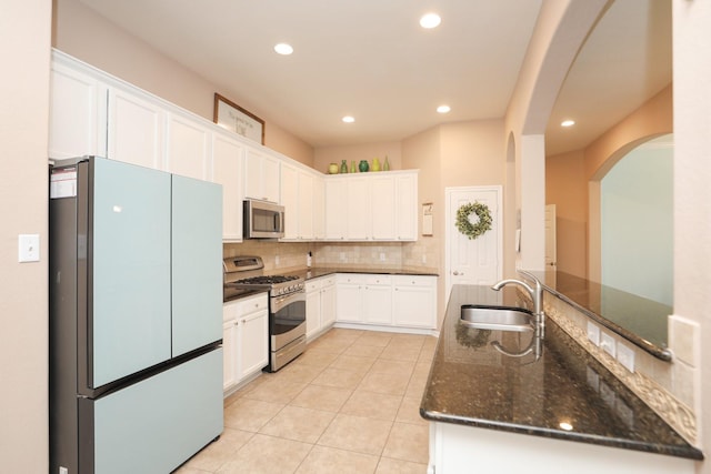 18123 Quarry Vale Dr, Cypress, TX 77429 - kitchen with stainless steel appliances, a sink, arched walkways, tasteful backsplash, and light tile patterned flooring