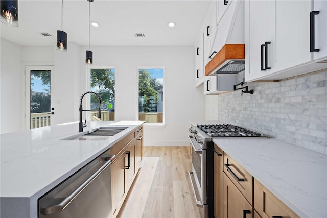 2206 Bleker St, Houston, TX 77026 - kitchen featuring stainless steel appliances, a sink, custom exhaust hood, light wood finished floors, and backsplash