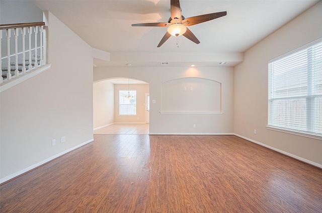 810 Dracena Ct, Richmond, TX 77406 - empty room featuring wood finished floors, ceiling fan, baseboards, arched walkways, and stairs
