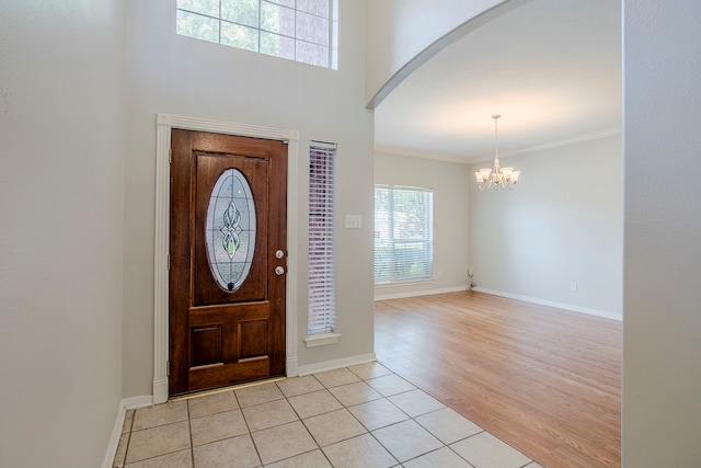 16511 Bluefin St, Crosby, TX 77532 - foyer with arched walkways, a chandelier, baseboards, ornamental molding, and light tile patterned floors