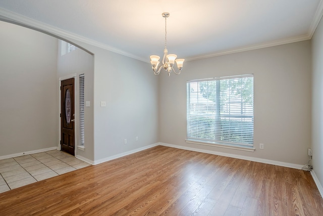 16511 Bluefin St, Crosby, TX 77532 - spare room with a chandelier, light wood finished floors, crown molding, baseboards, and arched walkways