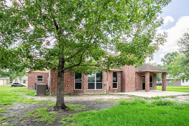 16511 Bluefin St, Crosby, TX 77532 - view of property hidden behind natural elements featuring a patio, central AC unit, a front yard, and brick siding