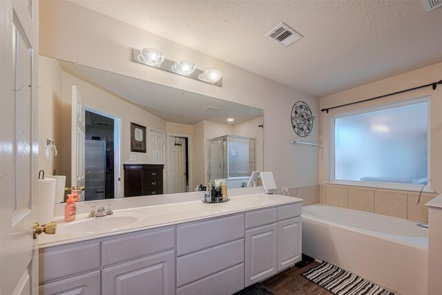1810 Macondray Dr, Humble, TX 77396 - full bathroom featuring a shower stall, double vanity, a bath, wood finished floors, and a textured ceiling