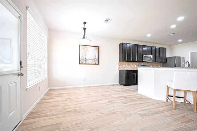 18827 Waverly Springs Ln, Cypress, TX 77429 - kitchen featuring appliances with stainless steel finishes, dark cabinets, healthy amount of natural light, light wood-style floors, and recessed lighting