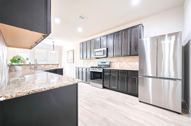 18827 Waverly Springs Ln, Cypress, TX 77429 - kitchen featuring appliances with stainless steel finishes, backsplash, light stone counters, a sink, and recessed lighting