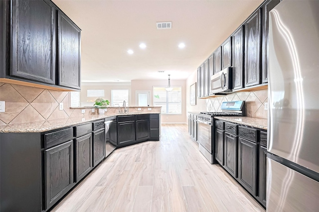 18827 Waverly Springs Ln, Cypress, TX 77429 - kitchen with stainless steel appliances, a peninsula, light stone counters, recessed lighting, and a sink