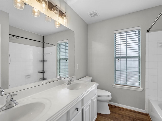 3910 Echo Mountain Dr, Kingwood, TX 77345 - bathroom with toilet, wood finished floors, double vanity, bathing tub / shower combination, and baseboards