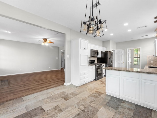 3910 Echo Mountain Dr, Kingwood, TX 77345 - kitchen featuring appliances with stainless steel finishes, white cabinetry, a chandelier, dark stone counters, and hanging light fixtures
