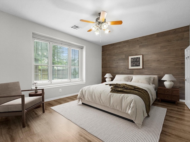 3910 Echo Mountain Dr, Kingwood, TX 77345 - bedroom with wood walls, an accent wall, baseboards, wood finished floors, and ceiling fan