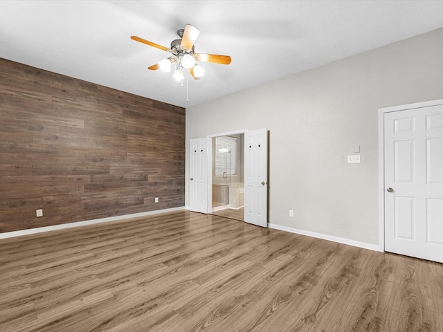 3910 Echo Mountain Dr, Kingwood, TX 77345 - unfurnished bedroom featuring wood finished floors, baseboards, ensuite bath, wooden walls, and ceiling fan