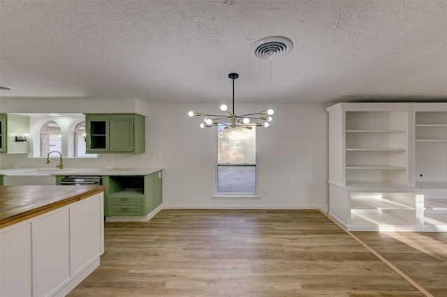 127 Red Bud Ln, Baytown, TX 77520 - unfurnished dining area with a textured ceiling, plenty of natural light, light wood finished floors, a chandelier, and a sink