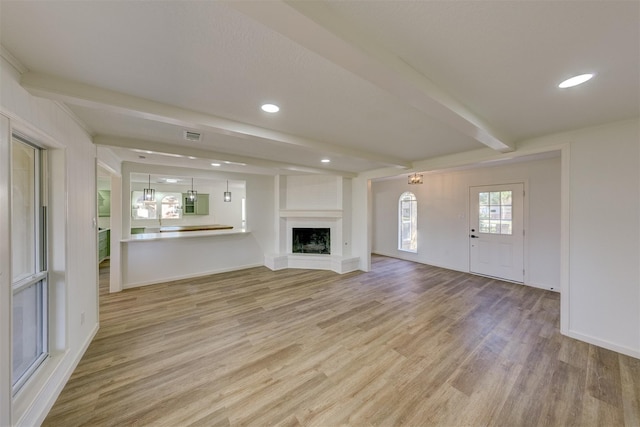 127 Red Bud Ln, Baytown, TX 77520 - unfurnished living room featuring beamed ceiling, light wood finished floors, a fireplace with raised hearth, recessed lighting, and baseboards