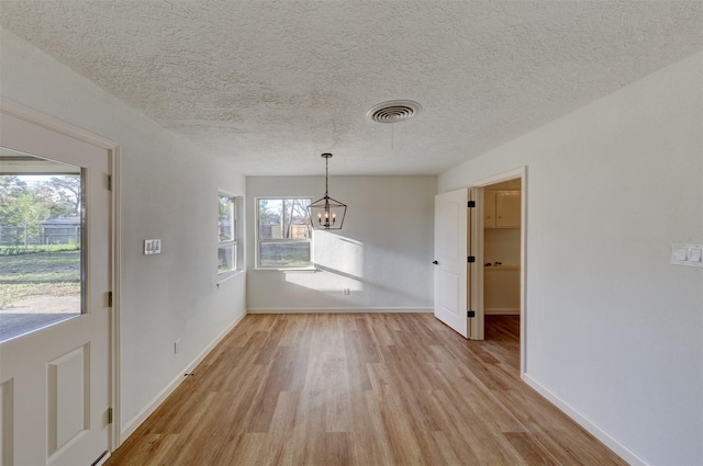 127 Red Bud Ln, Baytown, TX 77520 - unfurnished dining area with light wood-style flooring, a chandelier, baseboards, and a textured ceiling