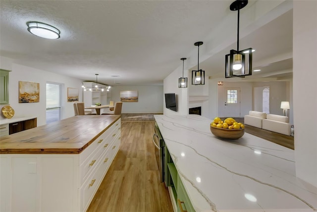 127 Red Bud Ln, Baytown, TX 77520 - kitchen with open floor plan, wood counters, light wood-style floors, a fireplace, and white cabinetry