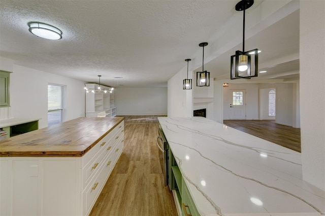 127 Red Bud Ln, Baytown, TX 77520 - kitchen with wood counters, open floor plan, light wood finished floors, a fireplace, and a textured ceiling