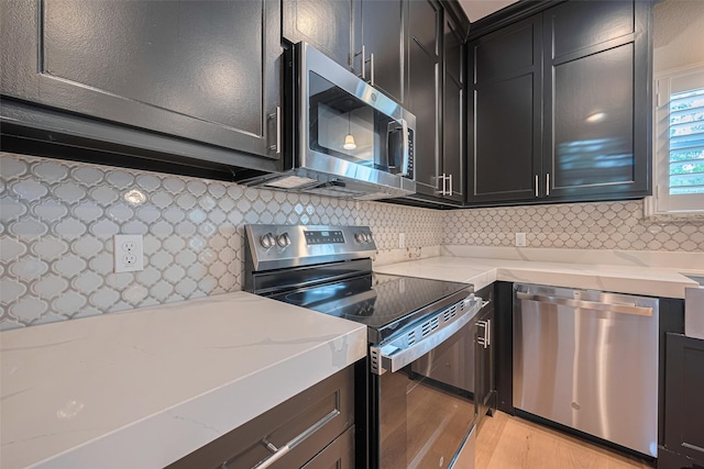 4523 Nexus Rd, Houston, TX 77053 - kitchen with stainless steel appliances, dark cabinets, light wood-style floors, and tasteful backsplash