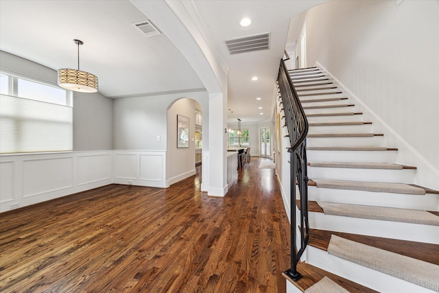 5204 Chestnut St, Bellaire, TX 77401 - foyer entrance featuring arched walkways, stairway, dark wood-style floors, wainscoting, and a decorative wall