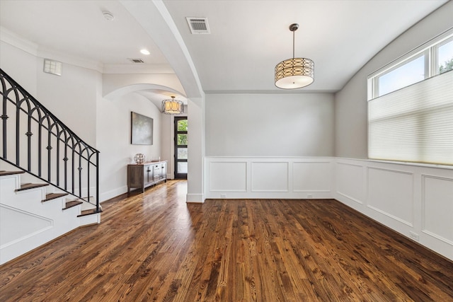 5204 Chestnut St, Bellaire, TX 77401 - empty room featuring arched walkways, dark wood-type flooring, a wainscoted wall, stairway, and crown molding