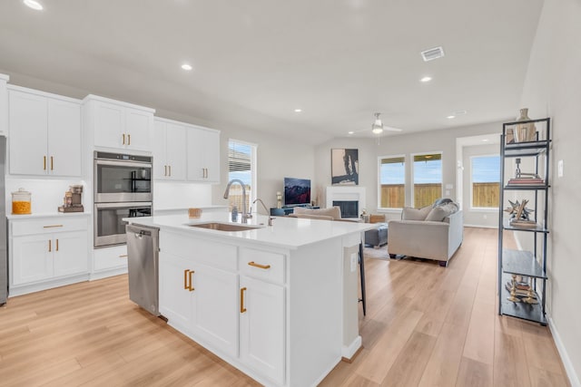 28403 Hannahs Harbor Ln, Katy, TX 77494 - kitchen featuring a sink, stainless steel appliances, light wood-style flooring, a fireplace, and a ceiling fan