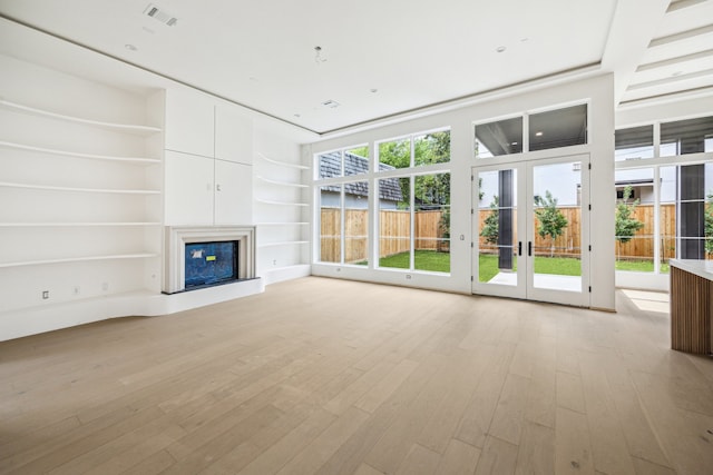 1656 Banks St, Houston, TX 77006 - unfurnished living room featuring a glass covered fireplace, light wood-style floors, built in features, and french doors