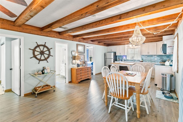 334 Bay Ave, Surfside Beach, TX 77541 - dining area with a chandelier, beam ceiling, light wood-style floors, and baseboards
