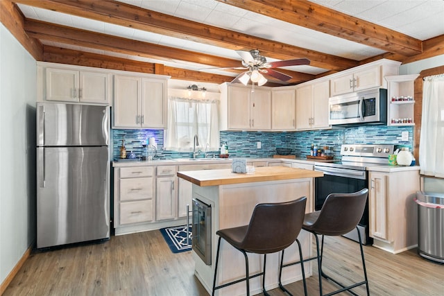 334 Bay Ave, Surfside Beach, TX 77541 - kitchen featuring appliances with stainless steel finishes, a sink, backsplash, beamed ceiling, and a kitchen island