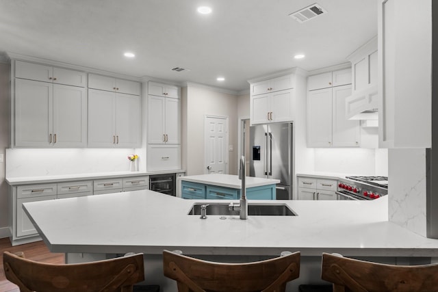 14 Brywood Pl, The Woodlands, TX 77382 - kitchen with premium appliances, a sink, light countertops, recessed lighting, and a kitchen breakfast bar