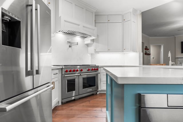 14 Brywood Pl, The Woodlands, TX 77382 - kitchen with appliances with stainless steel finishes, light countertops, wood finished floors, white cabinetry, and crown molding
