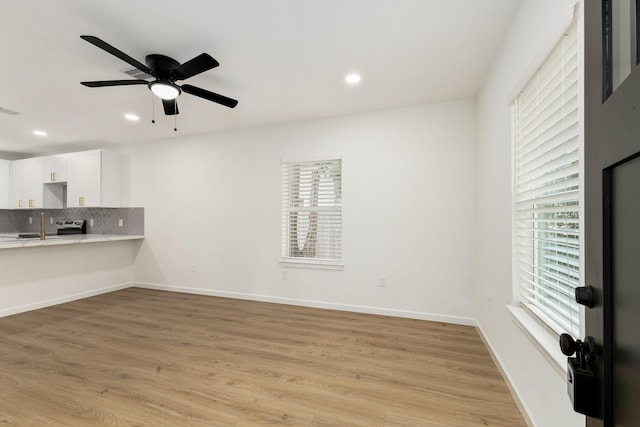 509 W Sixth St, Brenham, TX 77833 - unfurnished living room with plenty of natural light, light wood-style floors, ceiling fan, recessed lighting, and baseboards