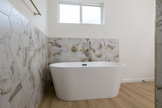 509 W Sixth St, Brenham, TX 77833 - bathroom featuring tile walls, a soaking tub, wood finished floors, and a wainscoted wall