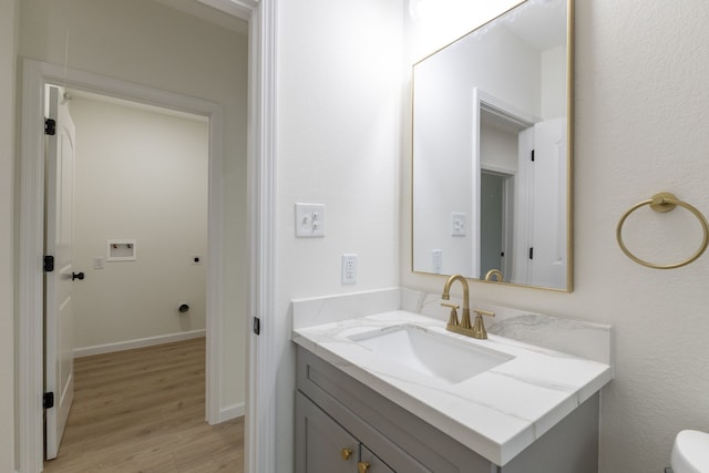 509 W Sixth St, Brenham, TX 77833 - bathroom featuring wood finished floors, vanity, toilet, and baseboards
