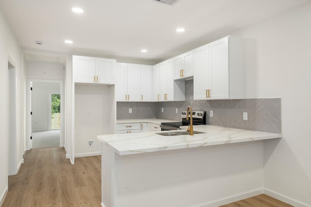 509 W Sixth St, Brenham, TX 77833 - kitchen featuring a sink, light stone counters, a peninsula, light wood-style floors, and white cabinetry