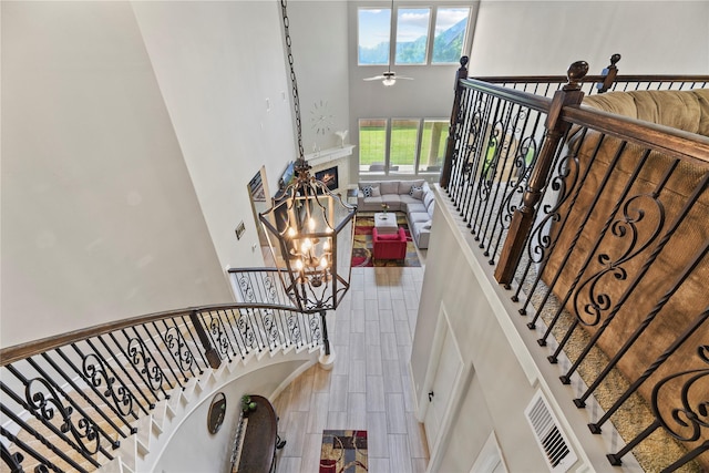 3310 Ralston Edge Ln, Houston, TX 77059 - stairway featuring a towering ceiling, a lit fireplace, ceiling fan, a chandelier, and tile patterned floors