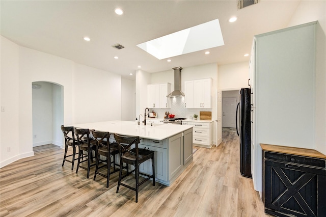 12006 Bright Landing Ct, Pearland, TX 77584 - kitchen featuring wall chimney range hood, freestanding refrigerator, light wood-type flooring, light countertops, and recessed lighting